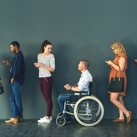 Personas haciendo fila con una persona en silla de ruedas en el medio